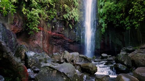 Ruhiger Wasserfall, der inmitten tropischer Vegetation die Vulkanklippe hinunterstürzt