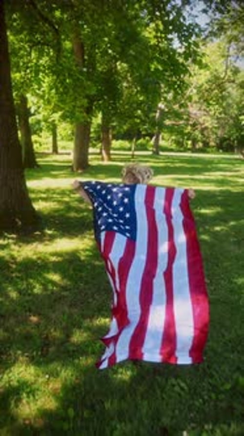 Child Runs with American Flag in Park on Sunny Day