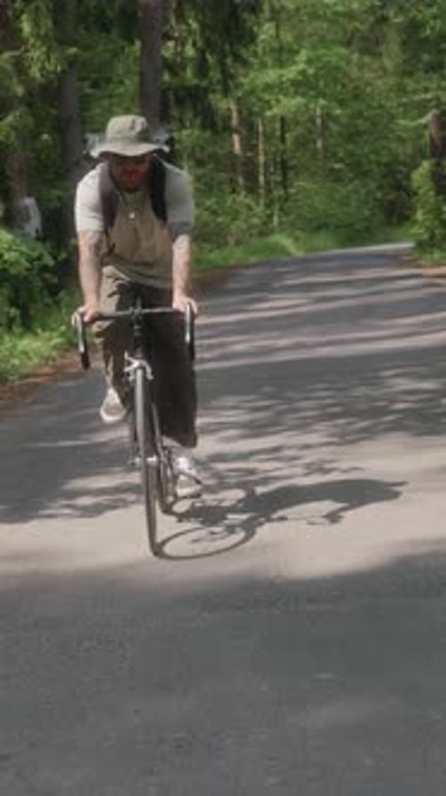 Cyclist Rides Toward Camera Through Forest Road