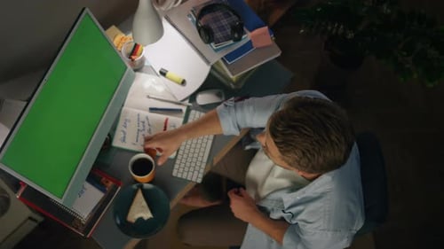 Young Adult Presenting on Green Screen Computer at Desk