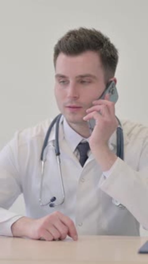 Young Doctor Talking on Phone in Clinic, vertical video