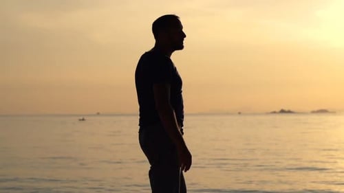 Silhouette of a man enjoying a relaxing sunset stroll on a tropical beach
