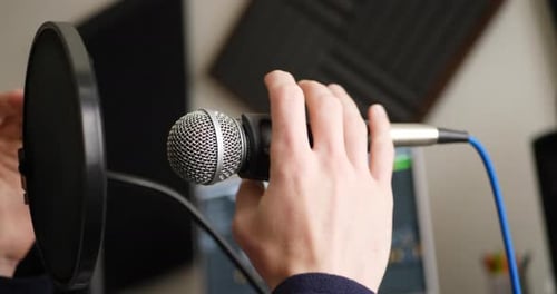Nahaufnahme eines Gesangsmikrofons und eines Popfilters, während eines Podcasts ein Radiogast hineinspricht r