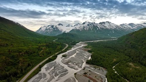 Footage above the shallow river flowing along the verdant mountains.