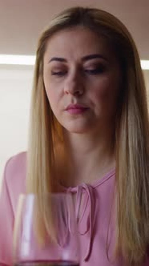 Upset Woman Looks at Glass with Wine Suspecting Poisoning