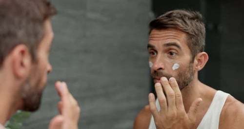 Man Applying Moisturizer to Face in Bathroom