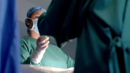 Diverse female and male surgeons in masks passing surgical tools during operation, slow motion