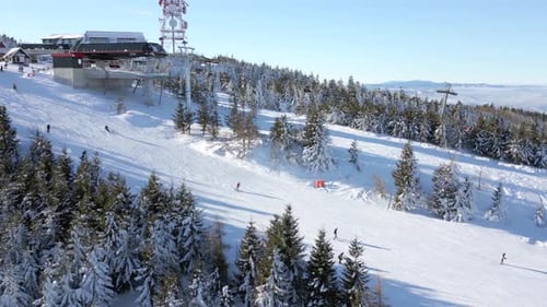 Aerial View of Snowy Ski Resort with People Skiing Down the Slope on a Sunny Day