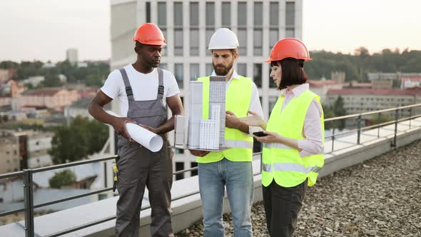Three Project Managers Inspecting Reduced Copy of Building ...
