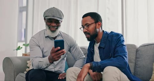Senior Man and Young Adult Man Look at Smartphone