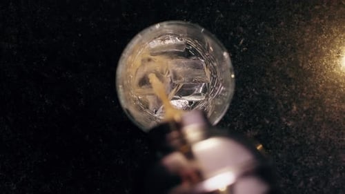 Pouring Cocktail into Glass with Ice Cubes
