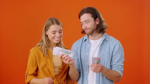 Couple Counting Stolen Money on Orange Background