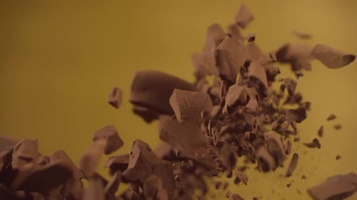 Falling Chocolate Pieces Against Yellow Background