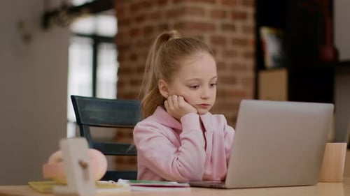 Junges Mädchen konzentrierte sich während einer Lernsitzung an einem gemütlichen Arbeitsplatz im Innenbereich auf den Laptop