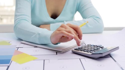 Woman designer using calculator working on architecture plan