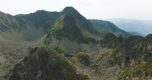 Small glacial blue lake at the bottom of a tall mountain peak, surrounded by mountain ranges and roc