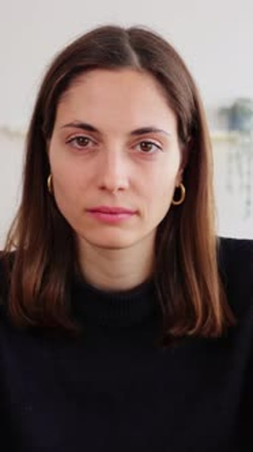 Portrait of Young Woman Smiling at Camera Sitting on Table at Home Studio