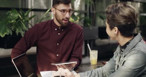 4k video footage of a young man and woman using a digital tablet during a business meeting at a cafe