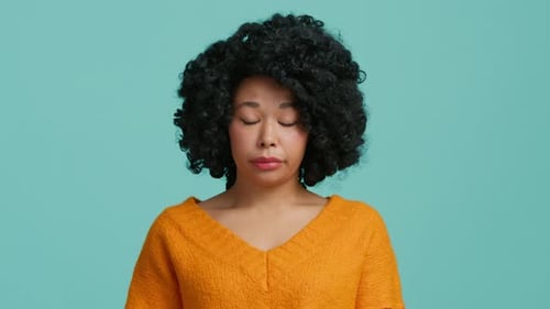 Jeune femme afro-américaine amusante, confuse, timide et honteuse, fille des années 20 dans des vêtements oranges