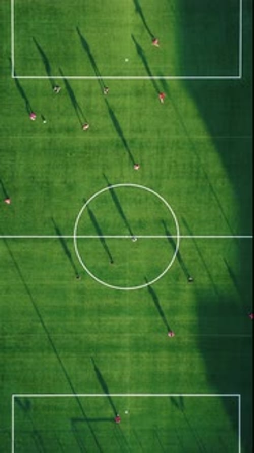 Soccer Match on Green Field at Sunset Light