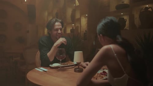 Couple profitant d'un dîner romantique dans un restaurant faiblement éclairé avec vin et nourriture