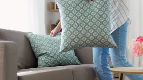 Household, Home Improvement and Cleaning Concept - Woman Arranging Cushions on Armchair