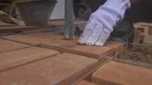 Construction worker placing brick on cement