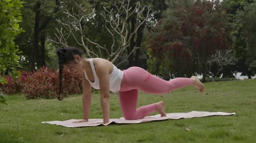 Young woman in public park doing yoga stretching daily practices exercises for body health and fitne