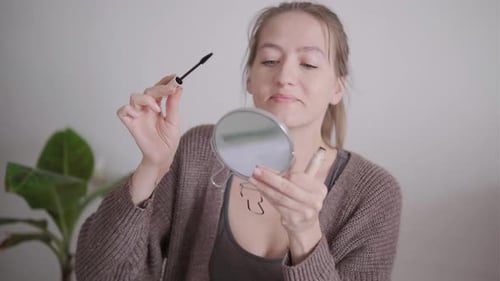Woman Applies Mascara Looking into Small Mirror