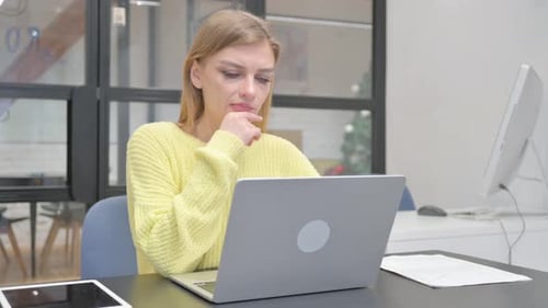 Woman Working on Laptop at Desk in Office