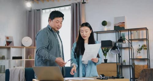 Man and woman students colleague in home office room and discussing report with charts with her.