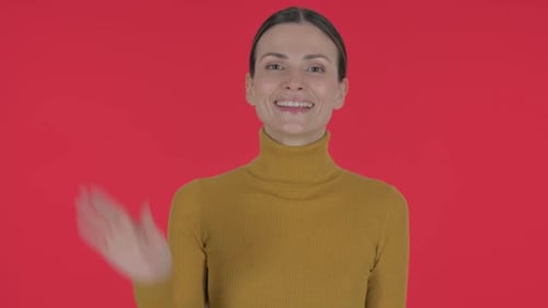 Smiling woman waving hand in front of red background