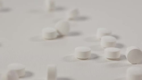 White pharmaceutical products, tablets, pills falling down against white background.