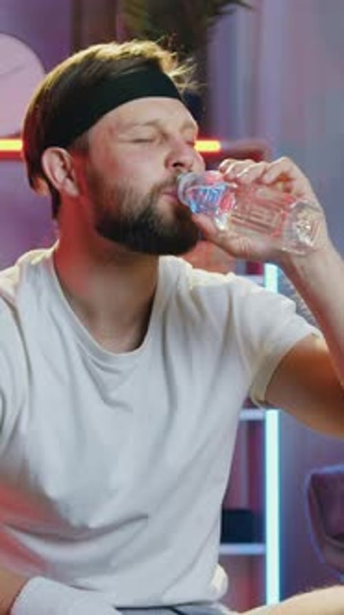 Man Drinking Water and Smiling After Workout at Home
