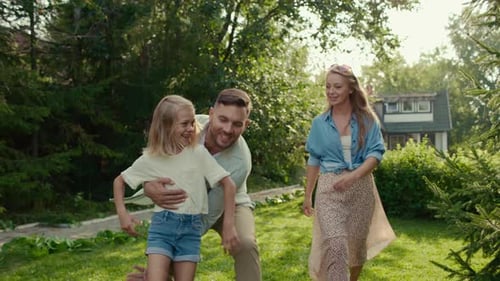 Happy Family Walking on Grass in the Sunlight