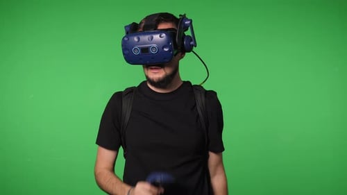 A Man Uses Virtual Reality Glasses to Play in a Studio on a Green Background
