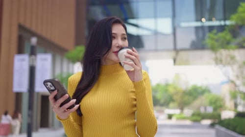 Asian young woman using smartphone while standing in the city.