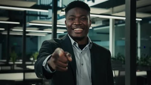 Glücklicher Geschäftsmann Afroamerikaner mittleren Alters posiert im Büro und zeigt auf den Zeigefinger der Kamera