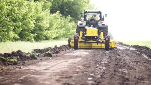 Grader arbeitet mit Traktor und ebnet die Feldstraße