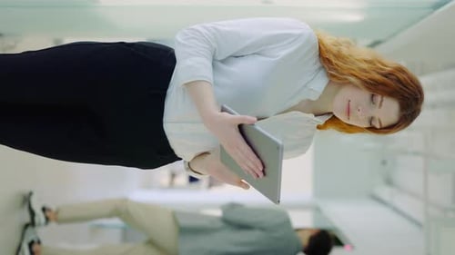 Vertical Video of the Attractive Businesswoman Using Digital Tablet While Standing in the Office