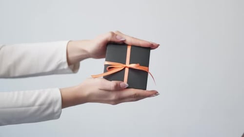 Hands Exchanging a Gift Box with Orange Ribbon
