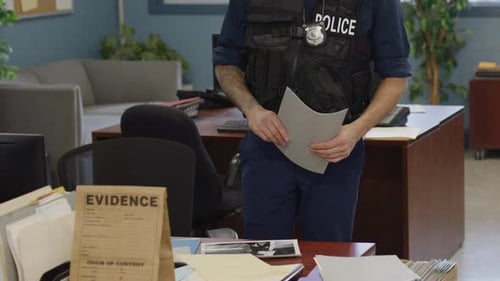 Close up hands of police officer going over documents at desk