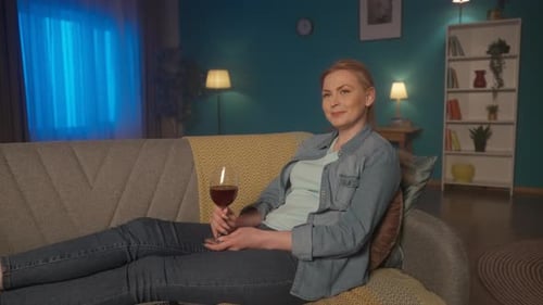 Woman Relaxes on Couch with Glass of Wine