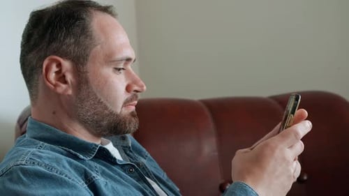 Adult Man Using Smartphone While Relaxing Indoors