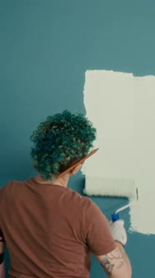 Vertical of Girl with Short Hair Repainting Wall during House Renovation