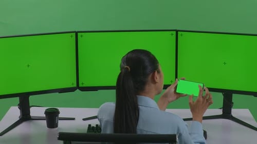 Woman Using Mobile Phone And Multiple Computer Monitor With Mock Up Green Screen In Green Screen