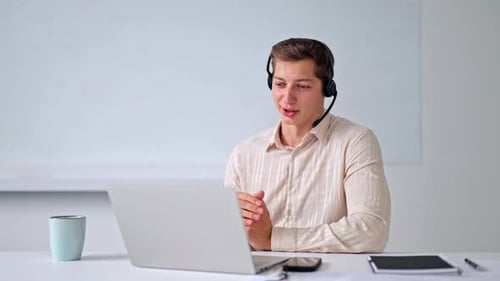 Man talking on video call with headset and laptop