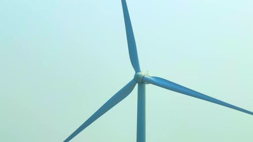 Majestic wind turbines stand tall against a soft sky, aerial view drone.