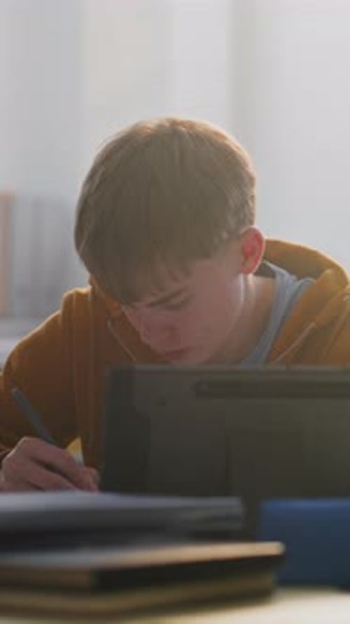 Focused Young Man Working on Tablet in Classroom Surrounded By Classmates