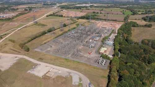 Aerial drone view of electrical power sub station, with powerlines and transformers and pylons,